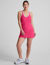 pink mini dress with a v-neckline, crossover strap detail in the back, and built-in shorts with pockets.